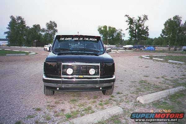 Black pickup truck with 'THE DARK SIDE OF THE MOON' banner on windshield parked in a lot