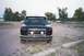 1994 Ford F-150 - A black pickup truck is parked in a gravel lot with trees and a fence in the background.
