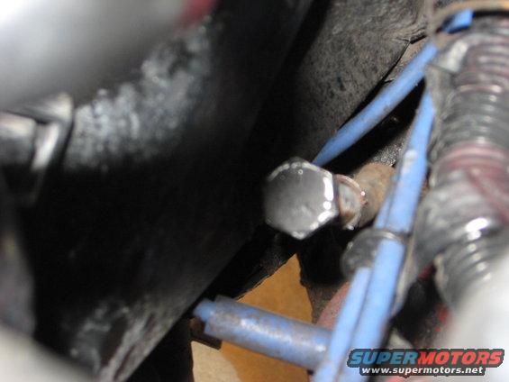 Close-up of engine bay with blue wires and a bolt