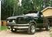 1994 Ford F-150 - This black Ford F-150 pickup truck is parked in front of a garage with trees in the background.