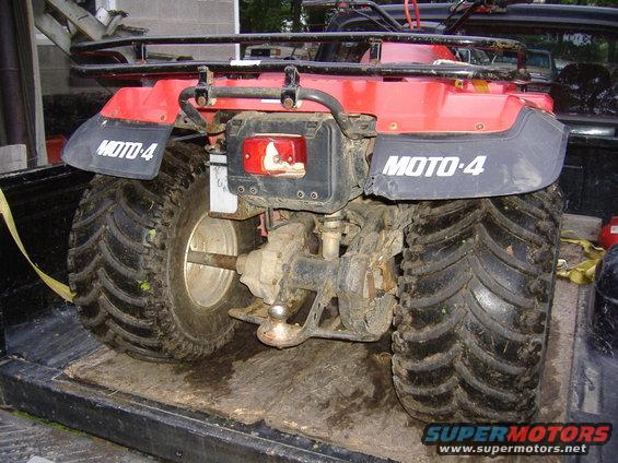 Red ATV rear view with MOTO-4 decals on fenders, large knobby tires, and a trailer hitch