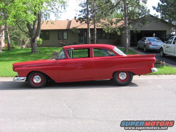 Red 1957 Ford Custom Sedan parked on street, side view