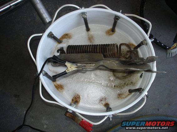 Electrolysis setup with metal parts in bubbly solution and alligator clips
