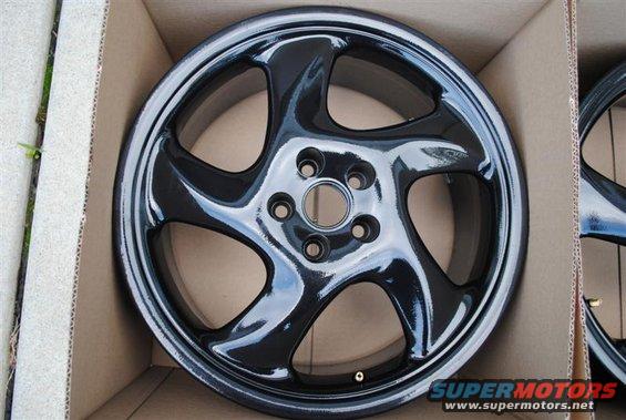Black five-spoke alloy wheel in cardboard box