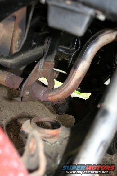 Close-up of rusted exhaust pipe and metal bracket under a vehicle