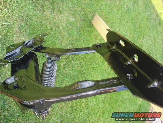 Black painted automotive suspension part with a coil spring, outdoors on grass