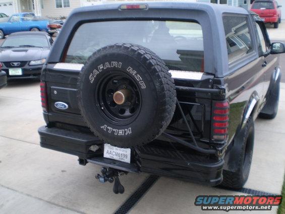 Black Ford Bronco with a spare tire mounted on the rear, seen from a rear-quarter angle