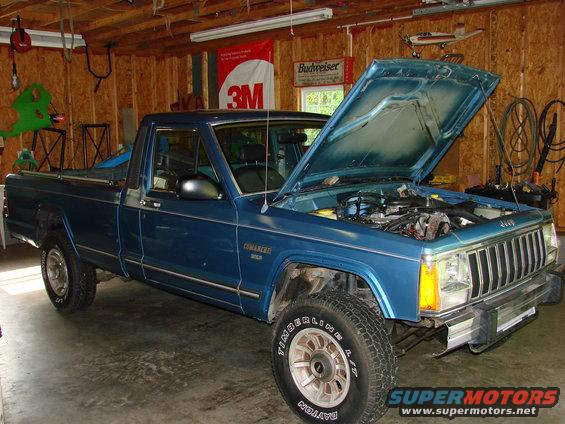 1991 Jeep Comanche pickup truck in garage, hood open showing engine