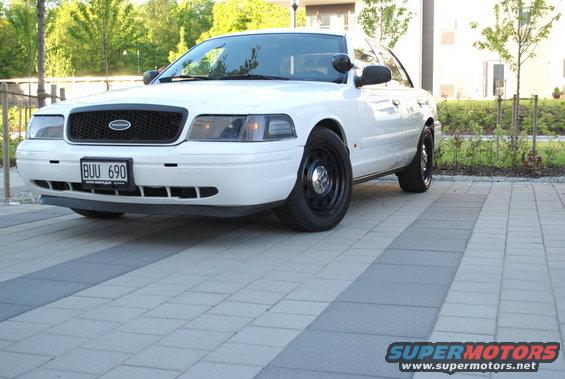 White 1998 Ford Crown Victoria with black grille and steel wheels, parked on a paved driveway