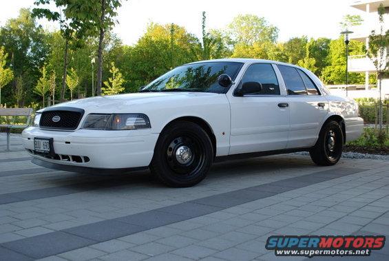 1998 Ford Crown Victoria police car parked on paved driveway, front quarter view