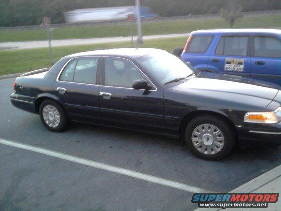 Dark sedan parked next to a blue SUV. The sedan has a chrome trim around the windows