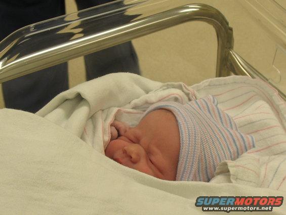 Newborn baby in hospital bassinet with striped hat