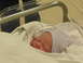 2001 Pontiac Trans Am - A newborn baby sleeps soundly in a hospital bassinet, wearing a striped hat and swaddled in blankets.