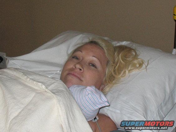 Woman in hospital bed wearing a newborn cap