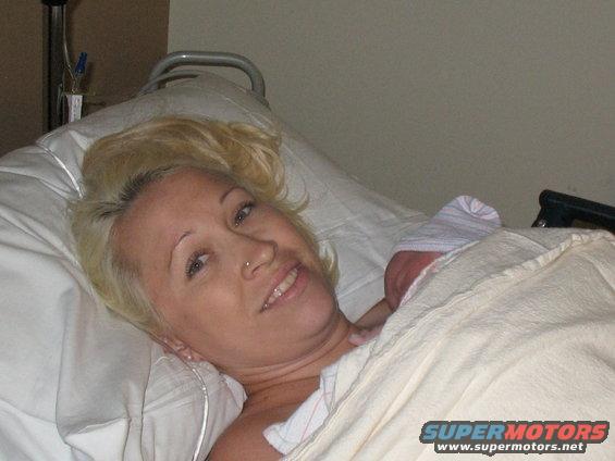 Woman in hospital bed with newborn baby wrapped in blanket