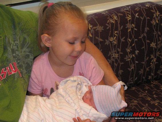 Young girl looking down at a newborn baby wrapped in a blanket