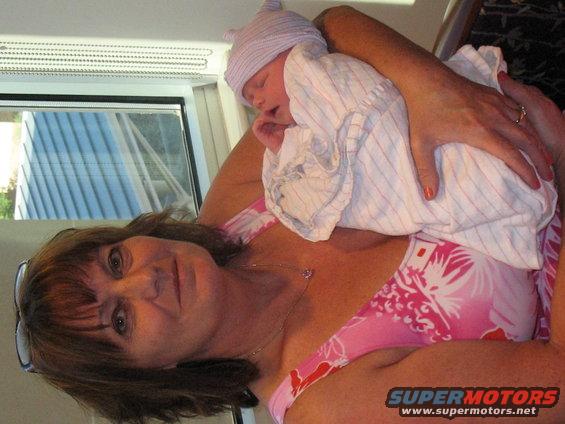 Woman holding a newborn baby wrapped in a blanket and wearing a hat
