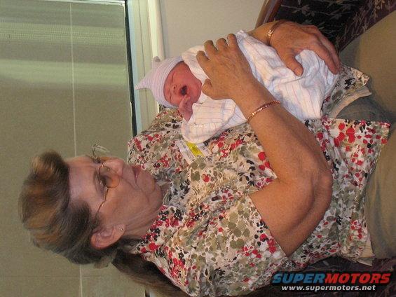 Grandmother holding a crying newborn baby wrapped in a blanket