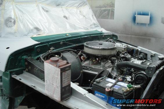 Engine bay of a truck being worked on, with plastic sheeting over the windshield and hood area