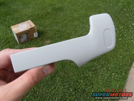 Gray car door handle held in hand, box in background