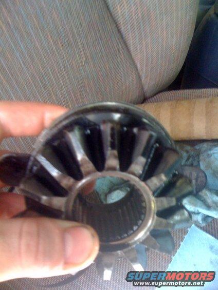 Differential gear held by a hand, with striped upholstery in the background