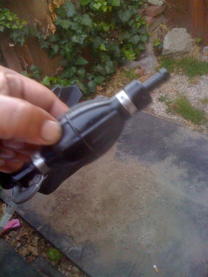 Hand holding black fuel primer bulb with silver bands