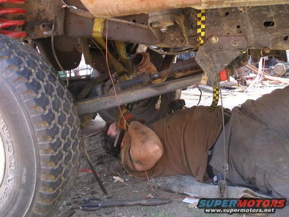 Mechanic lying on the ground working on the undercarriage of a large truck