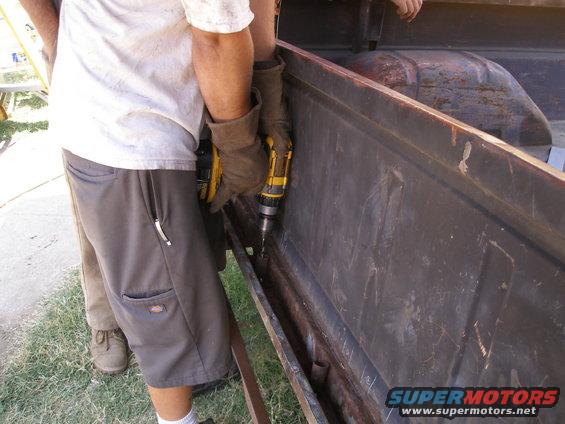 Rusty truck bed interior with a person drilling a hole