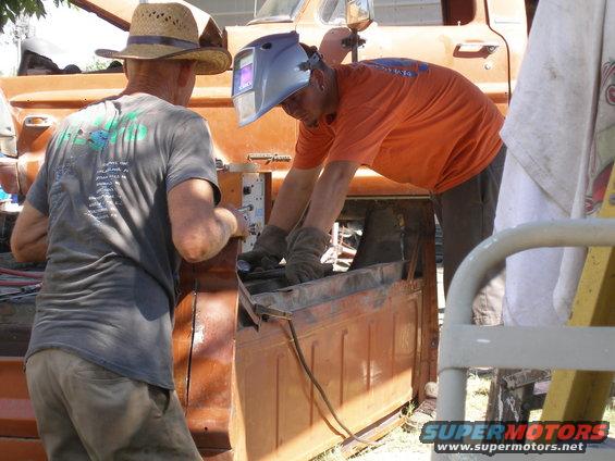 Men welding the bed of an orange truck