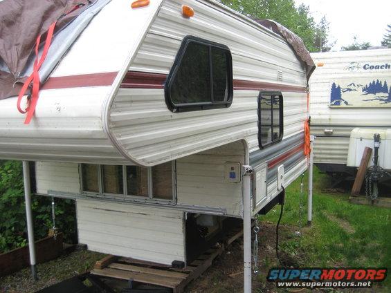 Camper on jacks, covered with tarp, with another RV in the background