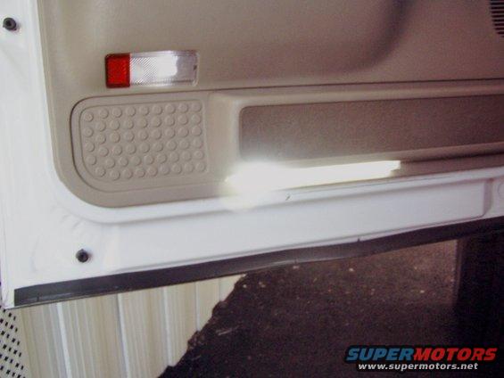 Interior door panel with a red and clear reflector and a textured speaker grille