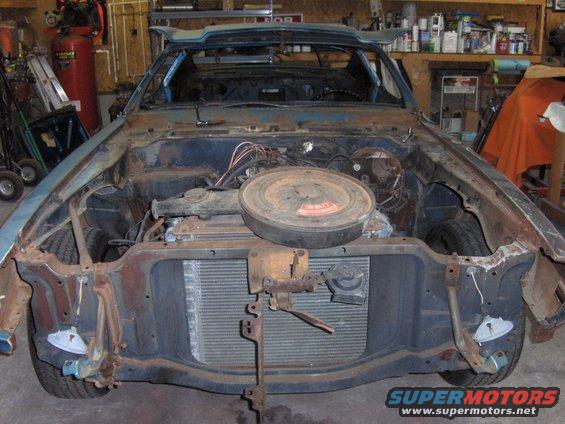 Car with front end removed, showing engine bay and radiator. Appears to be undergoing restoration