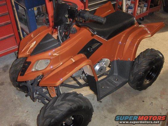 Orange ATV with black seat and handlebars, parked indoors
