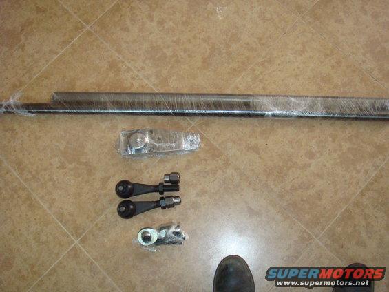 Several automotive suspension components, including a long bar and tie rod ends, wrapped in plastic