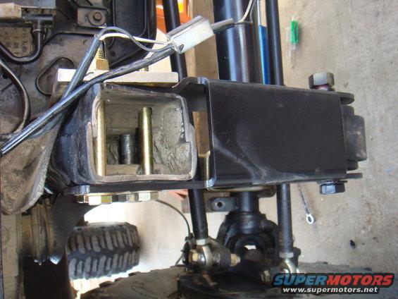 Close-up of a black suspension component with exposed internal metal and bolts