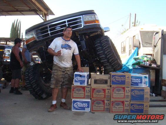1992 Ford Bronco lifted high on large tires, man holding beer, stacks of Bud Light and Budweiser boxes