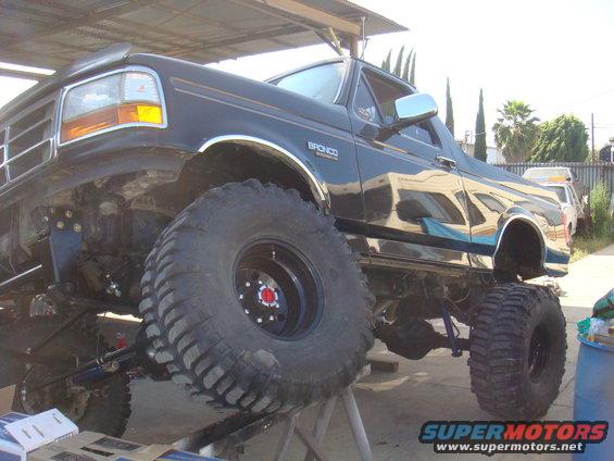 Black 1992 Ford Bronco with large off-road tires, lifted suspension, and chrome trim, viewed from a 3/4 front angle