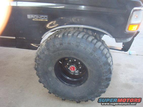 Black 1992 Ford Bronco with large off-road tire, front fender, and headlight