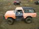 1978 Ford Bronco - A modified 1978 Ford Bronco sits in a muddy off-road area with other vehicles visible in the background.