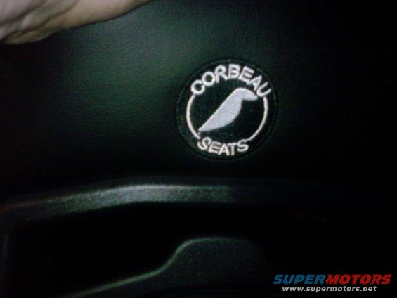 Close-up of a Corbeau Seats logo patch on black upholstery
