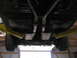 1985 Ford Mustang - The underside of a vehicle is visible, supported by yellow lift arms, with a dual exhaust system.