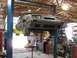 1985 Ford Mustang - A gray 1985 Ford Mustang is shown on a lift in a workshop, undergoing service.