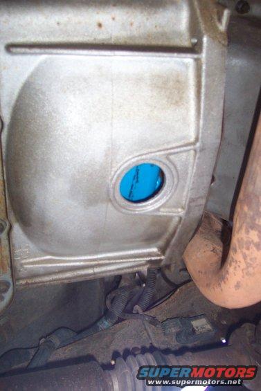 Close-up of a transmission housing showing a circular opening with blue fluid visible