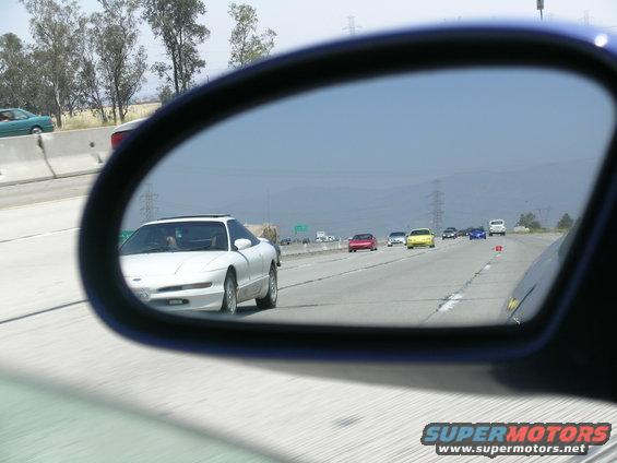 White 1993 Ford Probe in side view mirror on highway, other cars visible