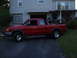 1997 Ford Ranger - A red pickup truck is parked in a driveway, carrying a dirt bike in its bed.