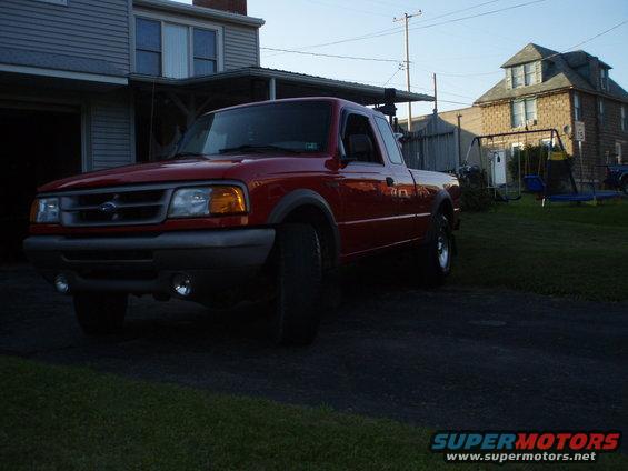 Red pickup truck parked in driveway, front 3/4 view, slightly dirty
