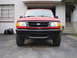 1997 Ford Ranger - A red 1997 Ford Ranger is parked in front of a house with its headlights on.