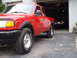 1997 Ford Ranger - A red 1997 Ford Ranger pickup truck is parked in front of an open garage with another vehicle inside.