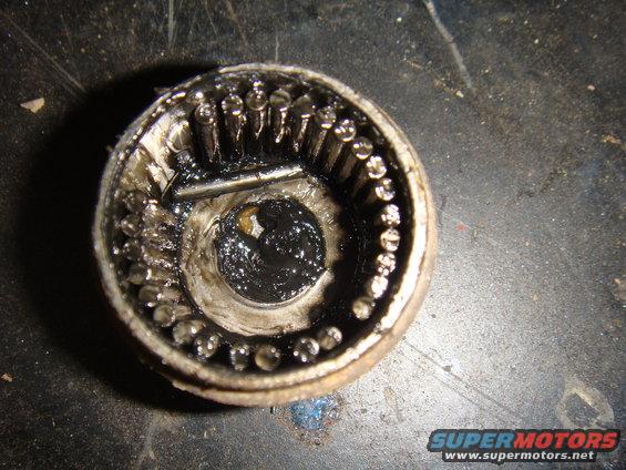Close-up of a heavily greased and worn wheel bearing with visible roller bearings and internal components