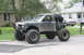 1984 Ford Bronco II - This heavily modified SUV, likely from the early 1980s, sits on oversized tires with a custom roll cage and bumper.